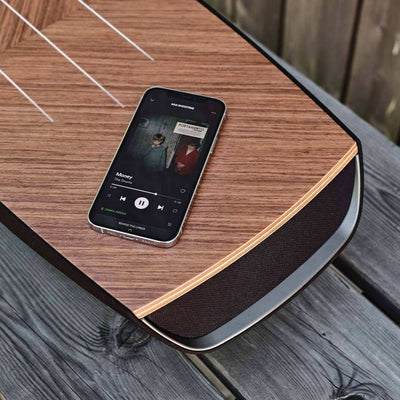 A sonus faber Omnia wireless speaker with a smartphone streaming music to the device.
